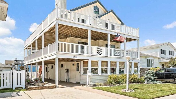 Une maison à deux étages avec un balcon, un garage et un jardin devant.