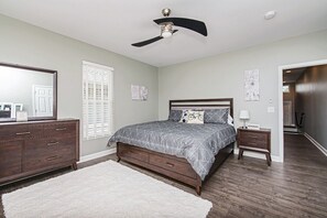 A bedroom with a bed, dresser, nightstand, and ceiling fan. - The Cycle Inn - on the Monon Trail Downtown Indy (Indianapolis)