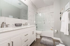 A modern bathroom with a marble vanity, a glass shower enclosure, and a white toilet. - The Cycle Inn - on the Monon Trail Downtown Indy (Indianapolis)