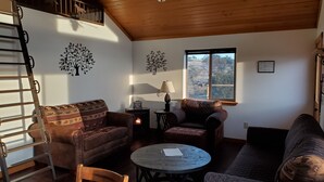 Ein gemütliches Wohnzimmer mit Kamin, zwei Sofas, einem Couchtisch und einem Fenster mit Blick.