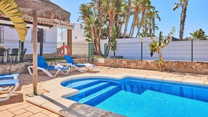 A swimming pool with lounge chairs, a lifebuoy, and palm trees. - Chalet El Cancelín Conil de la Frontera by Ruralidays (Cádiz)