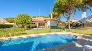 A swimming pool with a house in the background, surrounded by a green fence and trees. - Villa con Encanto Conil de la Frontera by Ruralidays (Cádiz)