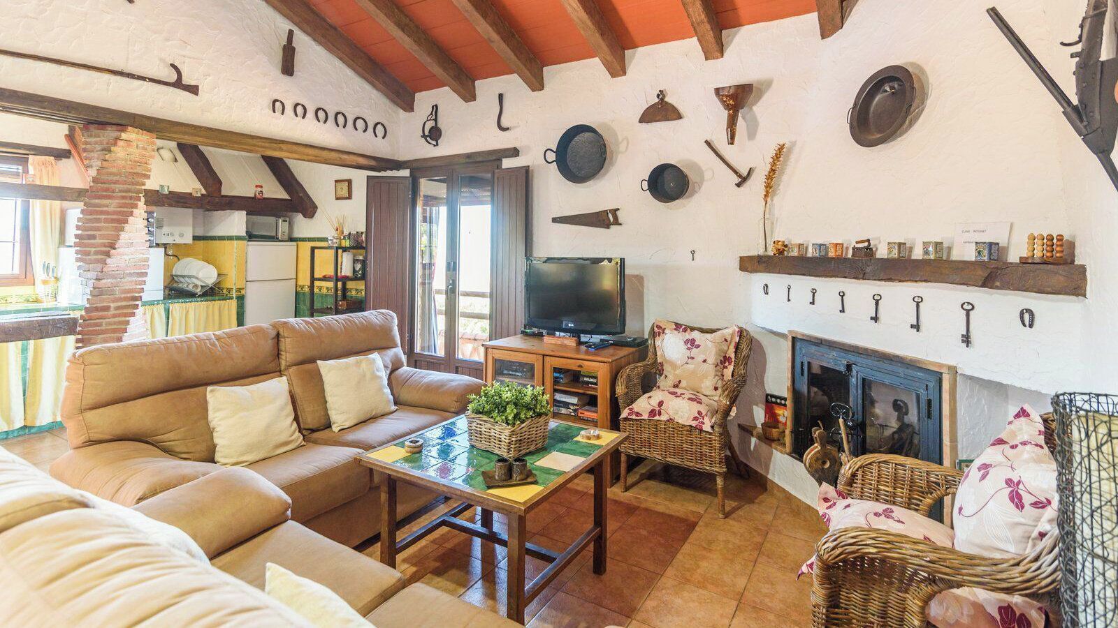 A cozy living room with a sofa, a television, wicker furniture, and a fireplace.
