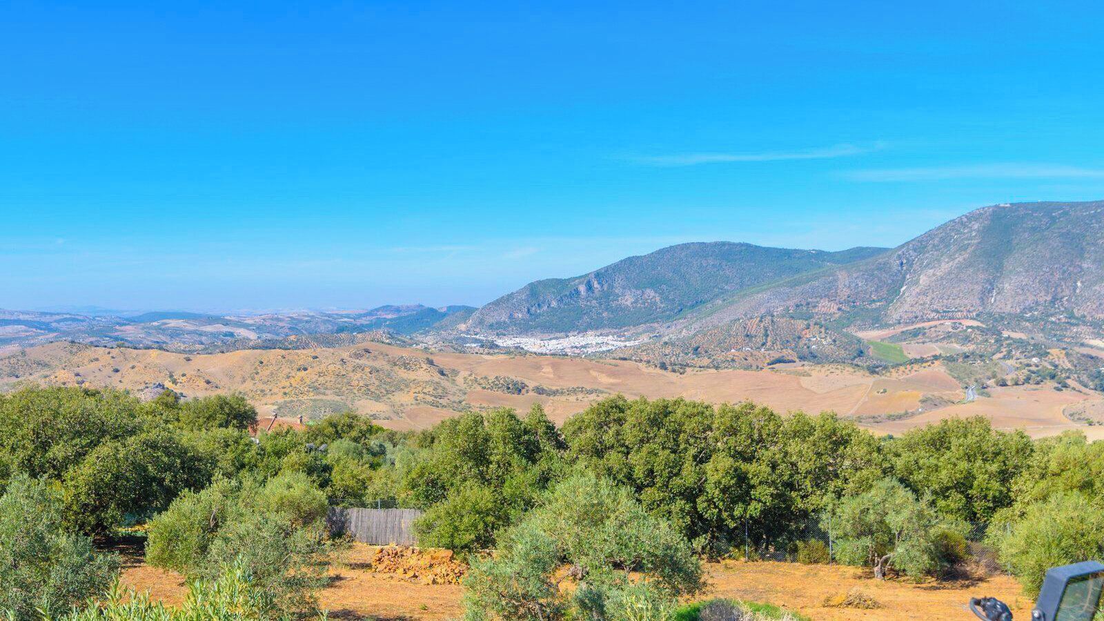A mountainous landscape with a dirt path and sparse vegetation.