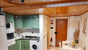 Een praktische keuken met een wasmachine, een magnetron en een eethoek met een tafel en stoelen.