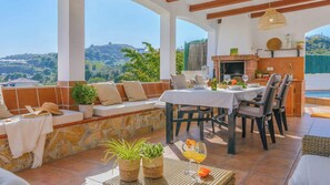A terrace with a dining table, chairs, a sofa, and a fireplace. - La Dehesa de Torrox by Ruralidays (Málaga)