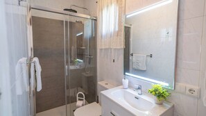 A modern bathroom with a glass-enclosed shower, a white sink, a mirror, and a potted plant. - La Dehesa de Torrox by Ruralidays (Málaga)