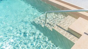 Een verwarmd zwembad, ligstoelen bij het zwembad