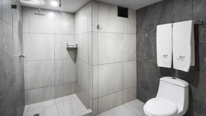 Une salle de bain moderne équipée d’une douche, de toilettes et d’un porte-serviettes.