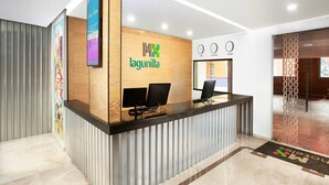 A modern reception desk with a logo, two computer monitors, and a clock. - Hotel MX lagunilla CDMX, Trademark Collection by Wyndham (Mexico City)