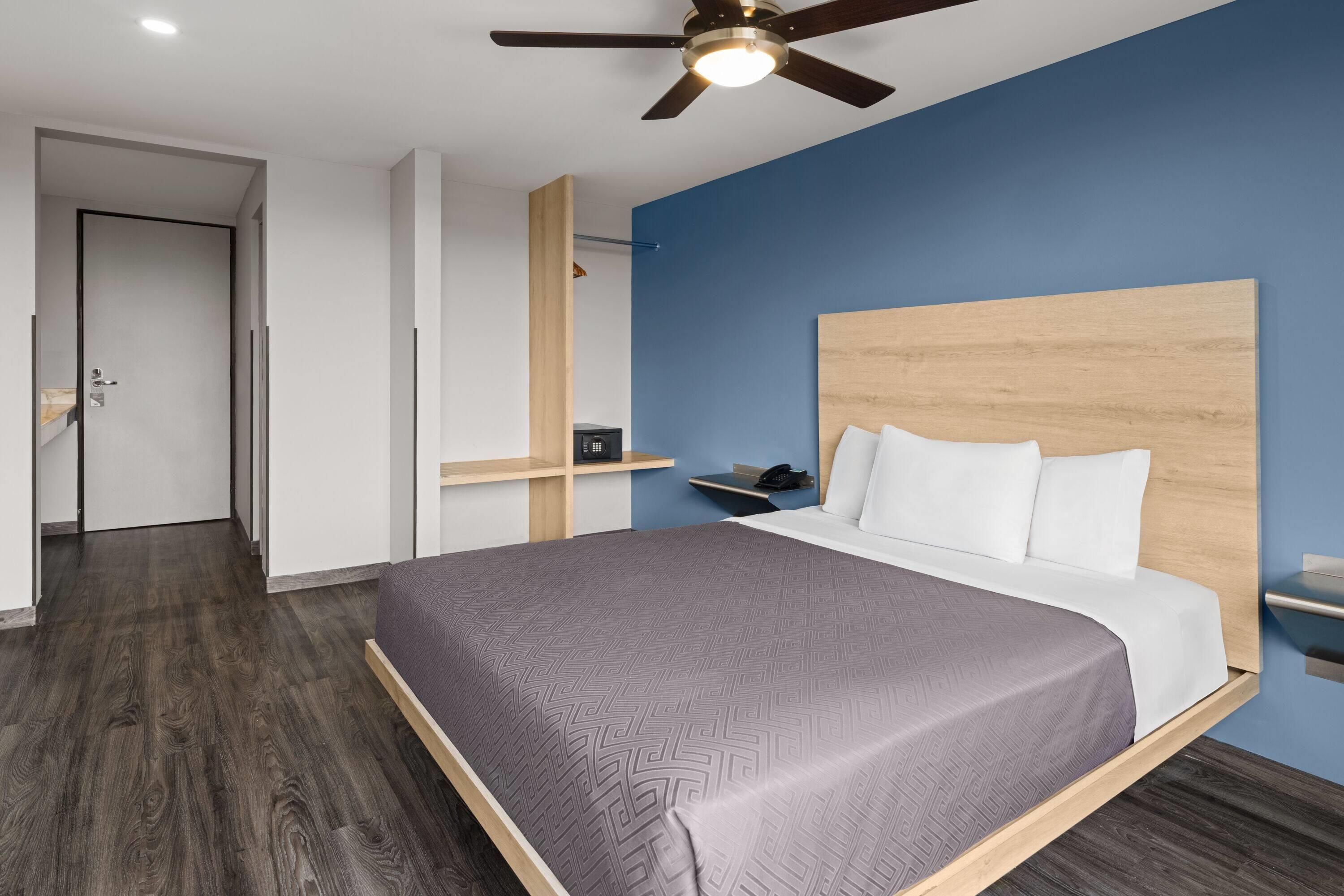 Une chambre à coucher moderne, comprenant un lit, un ventilateur de plafond, une table de chevet et une commode.