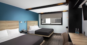 Une chambre d’hôtel avec deux lits, un bureau et une fenêtre.