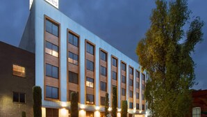 A modern hotel building with a prominent sign, multiple windows, and a well-lit facade. - Hotel MX lagunilla CDMX, Trademark Collection by Wyndham (Mexico City)
