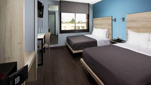 A hotel room with two beds, a desk, a chair, a TV, and a window with a city view. - Hotel MX lagunilla CDMX, Trademark Collection by Wyndham (Mexico City)