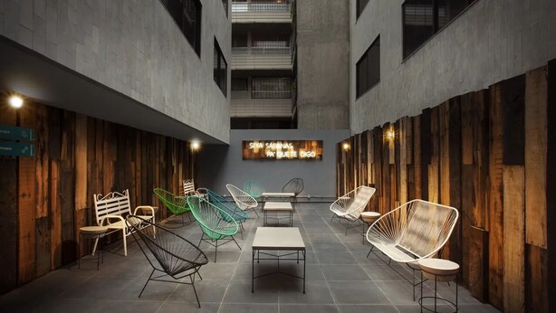 A modern interior with a central table and chairs, wooden walls, and a ceiling with exposed beams. - Hotel MX lagunilla CDMX, Trademark Collection by Wyndham (Mexico City)