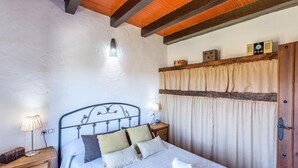 A bedroom with a bed, bedside tables, a lamp, a wooden headboard, a curtain, and a clock on the wall. - Jara de El Gastor by Ruralidays (Cádiz)