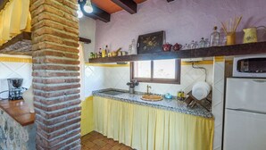A kitchen with a brick column, a window, a sink, and a refrigerator. - Jara de El Gastor by Ruralidays (Cádiz)