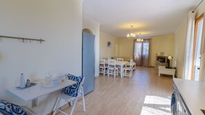 Un espacio habitable amplio con una mesa y sillas de comedor, una cocina equipada con refrigerador, y un área de comedor con candelabro.