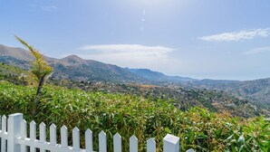 A white picket fence, lush green vegetation, and a mountainous landscape in the background.