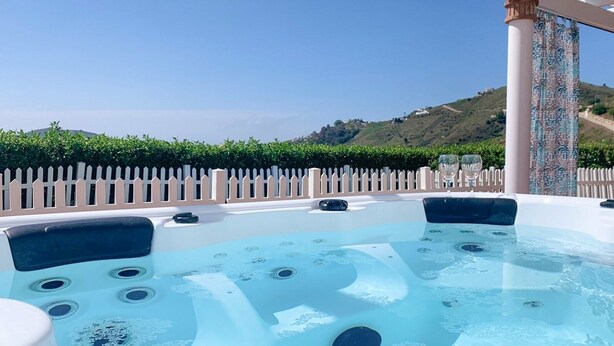 A hot tub with a clear view of a hilly landscape in the background.