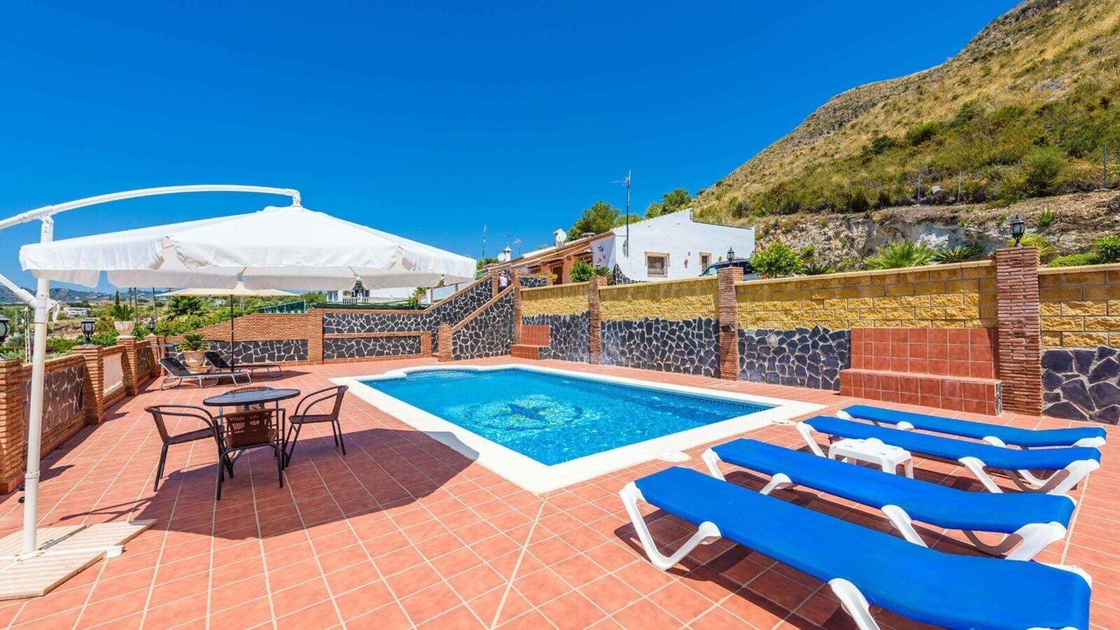 A rooftop pool area with a swimming pool, lounge chairs, and a table with chairs.