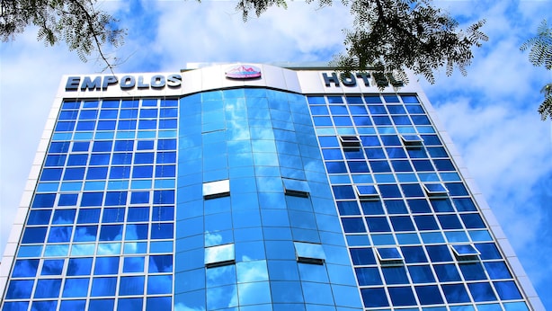 A modern hotel building with a glass facade and signage for "EMPOLOS HOTEL".