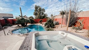 A hot tub and a swimming pool in a backyard with a red wall and various plants. - Welcome to Casa Lana !! (Gold Canyon)