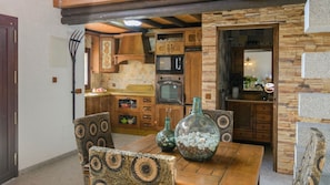 A cozy kitchen with wooden cabinets, a microwave, and a dining table with patterned chairs. - Villa Aperillo Frigiliana by Ruralidays (Málaga)