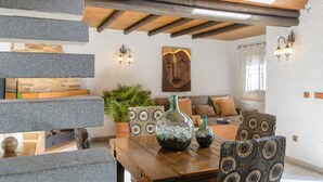 Uma sala de estar acolhedora com uma mesa de madeira, almofadas estampadas e um vaso decorativo.