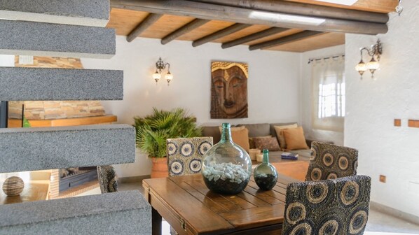 A cozy living room with a wooden table, patterned cushions, and a decorative vase. - Villa Aperillo Frigiliana by Ruralidays (Málaga)