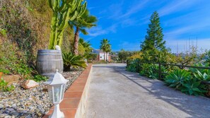 A paved pathway flanked by cacti, palm trees, and a wooden barrel. - Villa Aperillo Frigiliana by Ruralidays (Málaga)