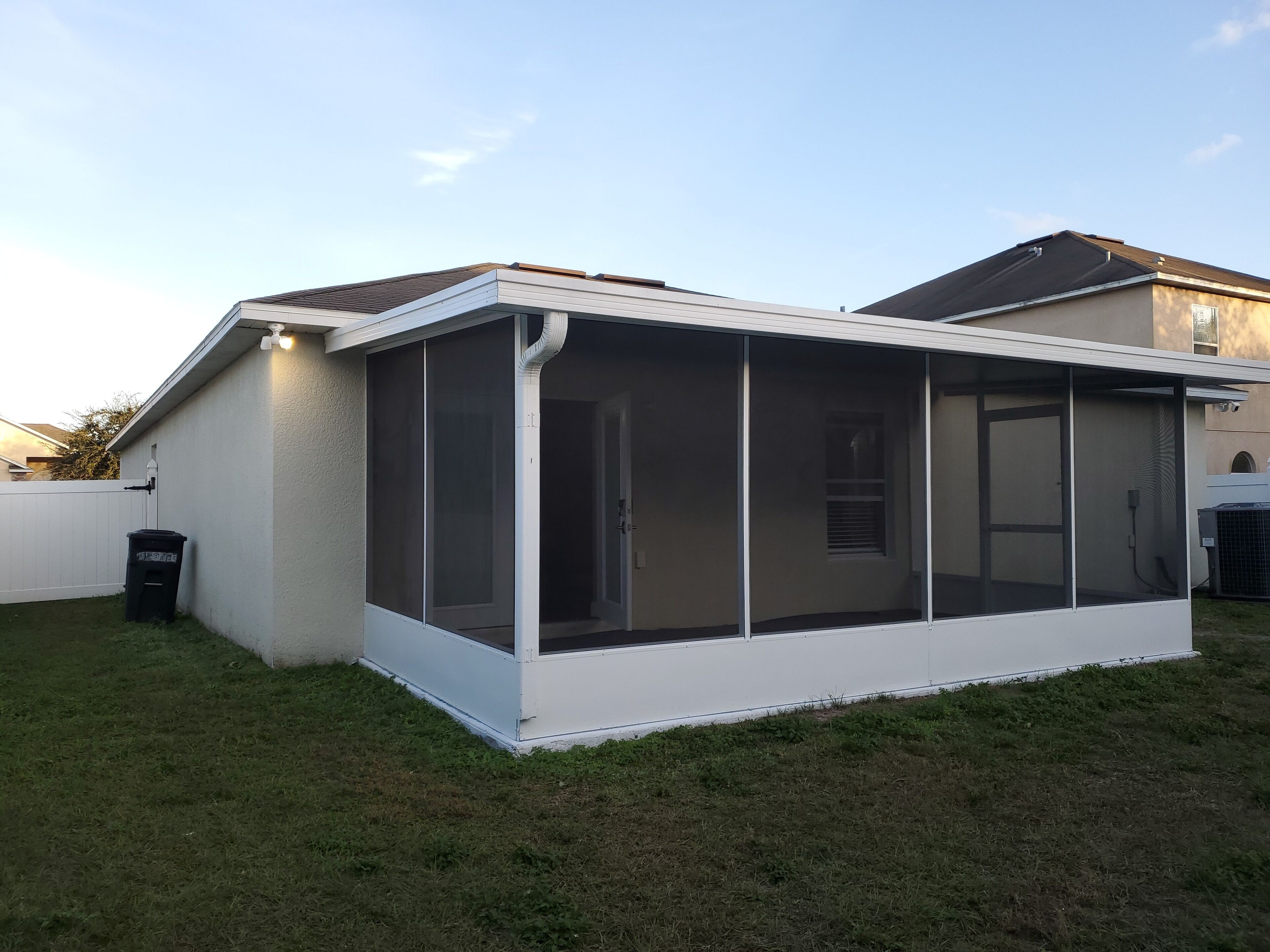 Une maison dotée d’un patio couvert, d’une façade blanche et d’une porte de garage visible.