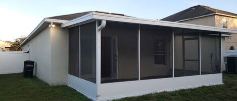 Une maison dotée d’un patio couvert, d’une façade blanche et d’une porte de garage visible.