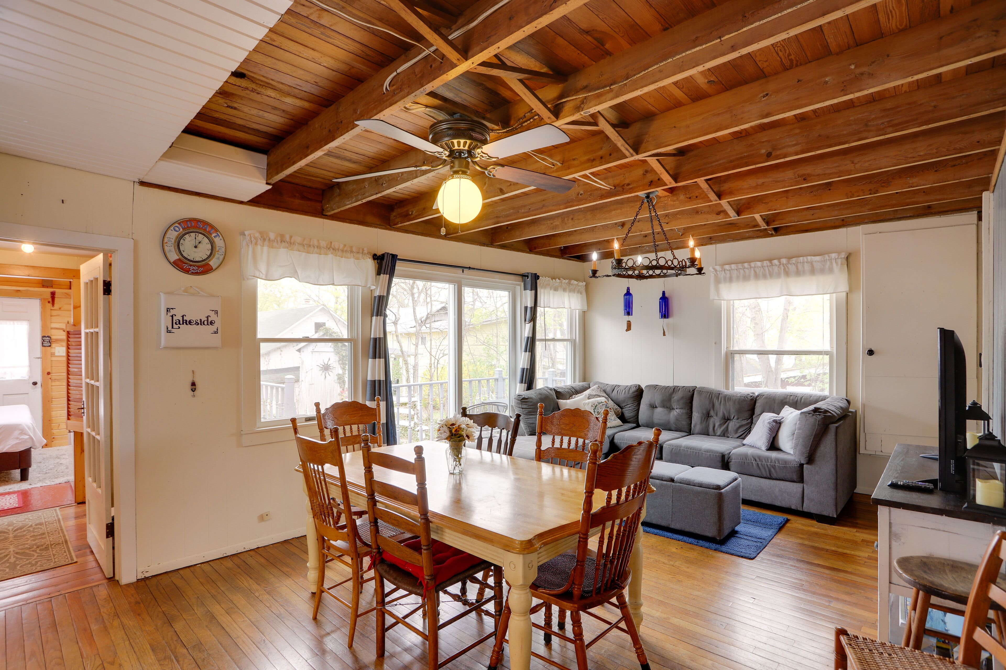 A dining area with a wooden table and chairs, a ceiling fan, and a chandelier.