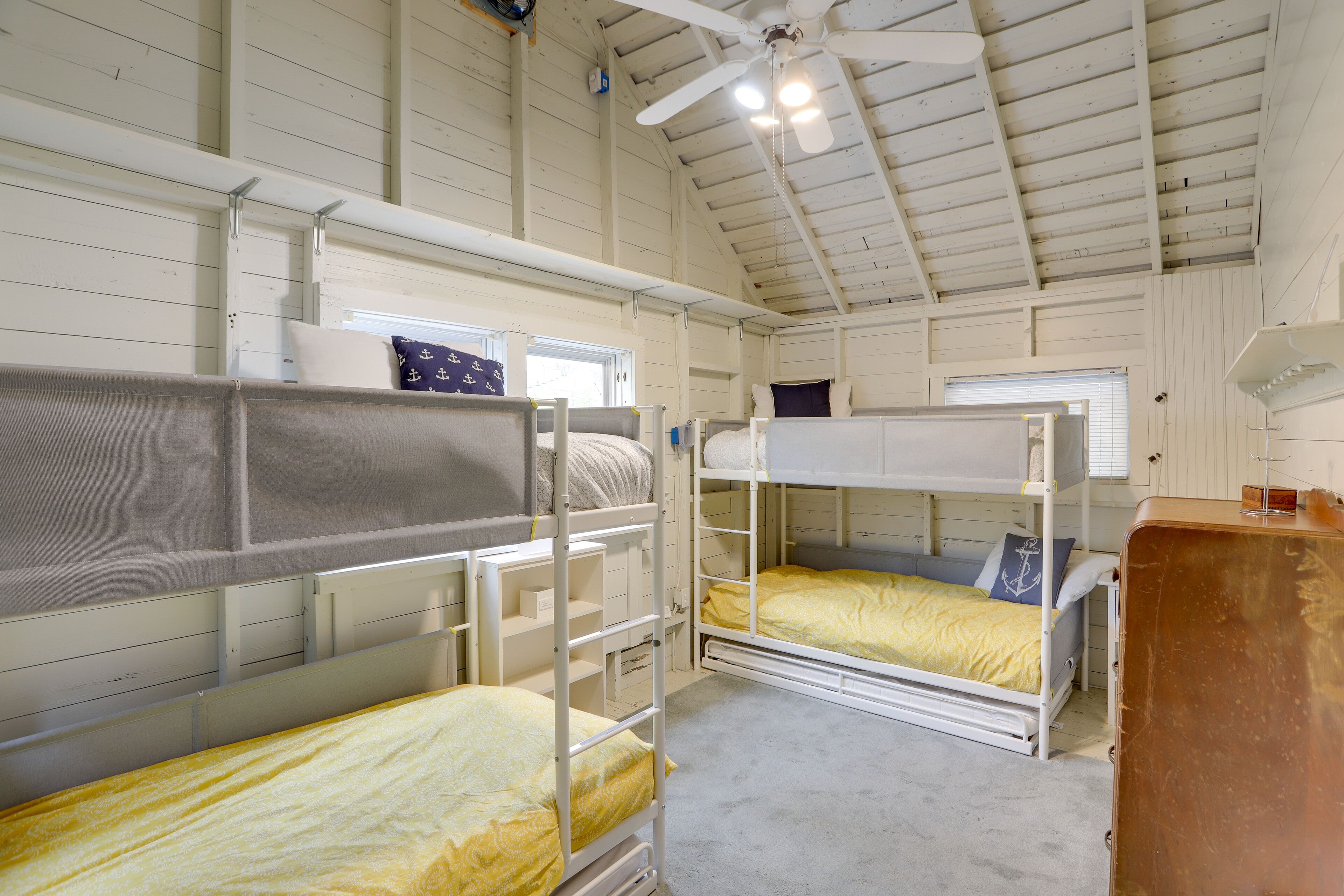 Une chambre avec trois lits superposés, un ventilateur de plafond et une fenêtre.
