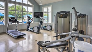 Une salle de sport équipée de tapis de course, de vélos elliptiques et d’appareils de musculation.