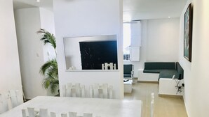 Un salon moderne avec une table à manger blanche, un canapé vert et un grand miroir.