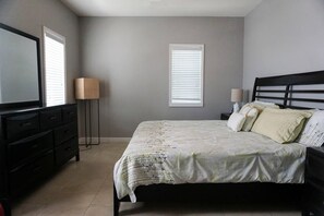 A bedroom with a bed, a dresser, a TV, and two bedside lamps.