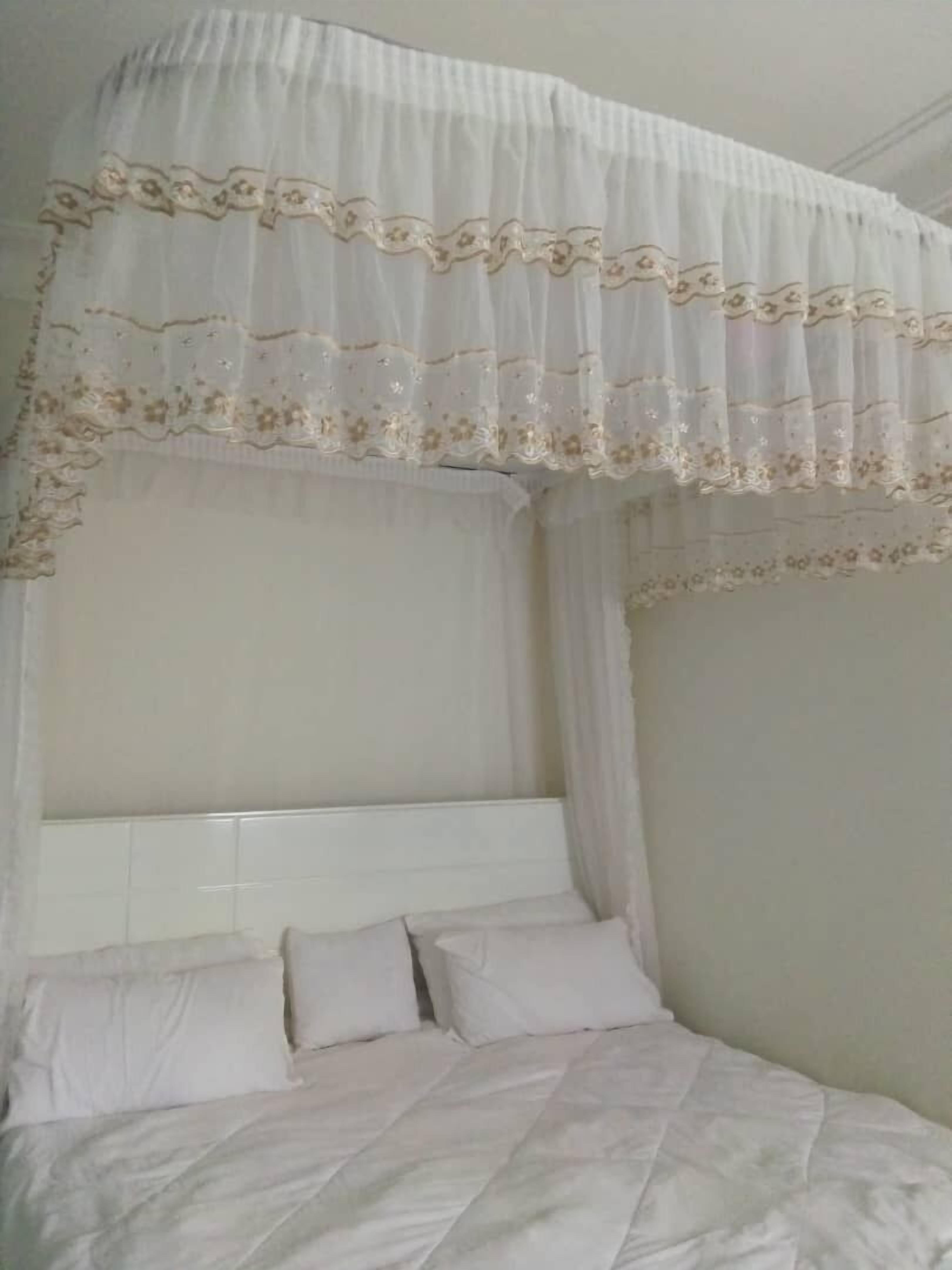 A bed with a canopy and white bedding.