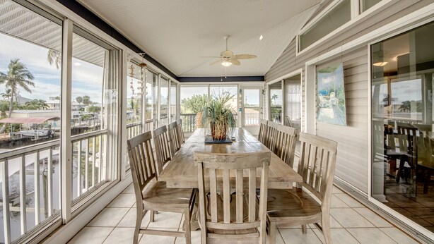 A spacious dining area with a large wooden table, multiple chairs, and a ceiling fan. - Tropical Oasis Pool Kayak Bikes fish from dock  (Matlacha)