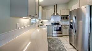A modern kitchen with stainless steel appliances, white cabinetry, and a central island. - Tropical Oasis Pool Kayak Bikes fish from dock  (Matlacha)