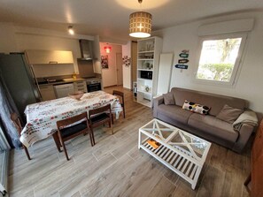 A compact living space with a dining area, kitchenette, and a sofa. - Great apartment near the lake and downtown (HOSSEGOR)