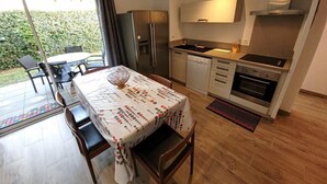 Une cuisine compacte avec un coin repas, comprenant un réfrigérateur, un four et un lave-vaisselle.