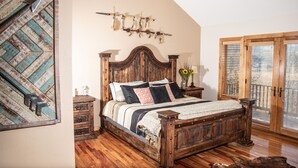 A bedroom with a wooden bed, a rustic wall decor, and a large window with blinds.