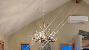 A dining area with a wooden table, chairs, a chandelier, and a clock on the wall.