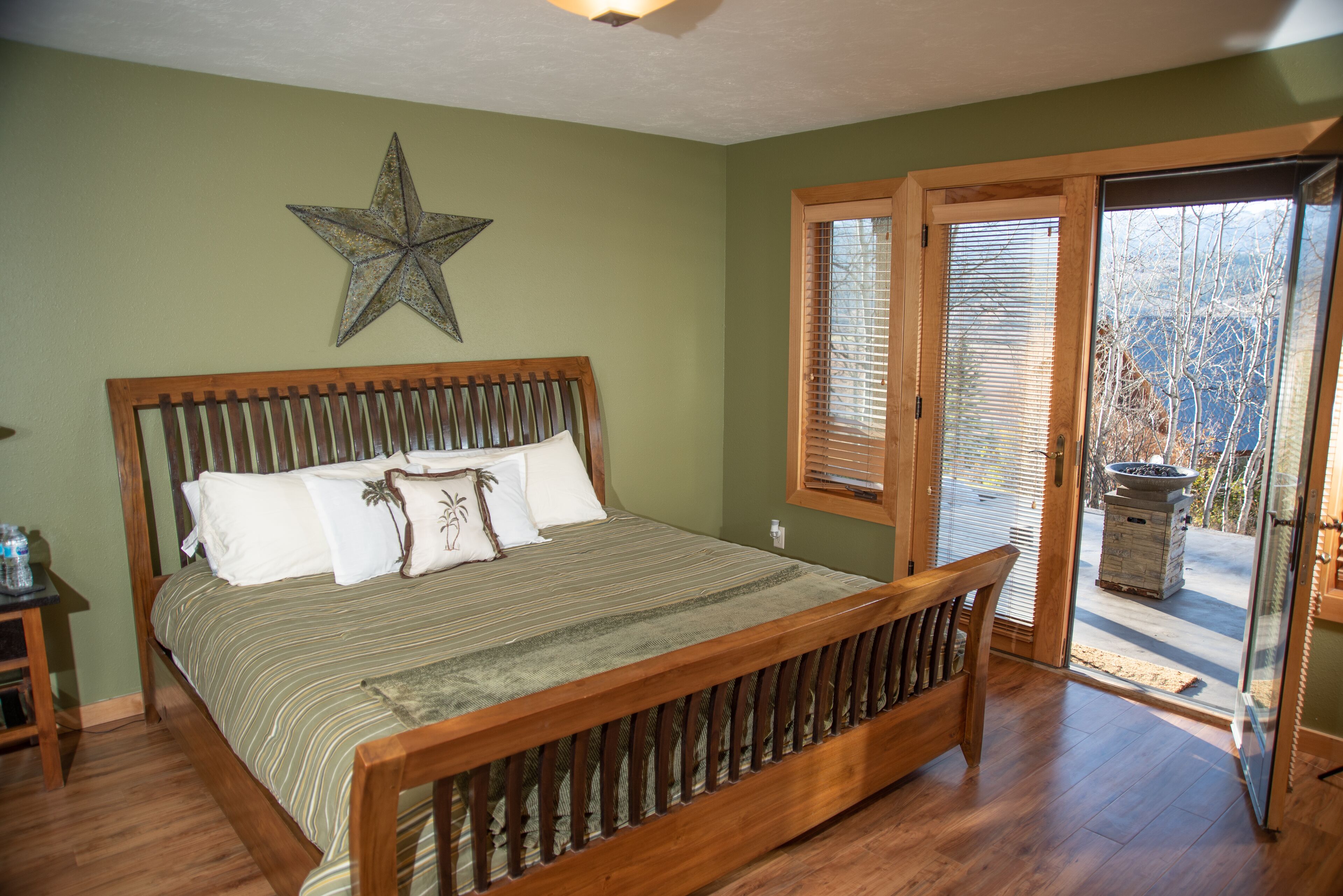 A bedroom with a wooden bed, a star decoration, and a view through a glass door.