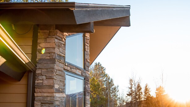A modern house with a stone facade, large windows, and a wooden deck.
