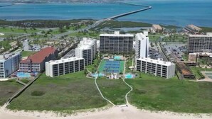 A resort with multiple high-rise buildings, a central pool area, and a beach with umbrellas.