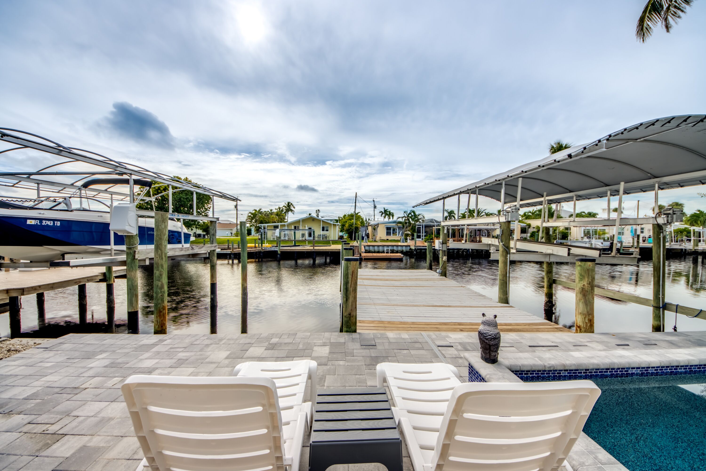 A marina with boats docked, a covered seating area, and a swimming pool.