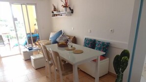 Un coin repas avec une table blanche, des chaises et un cactus.